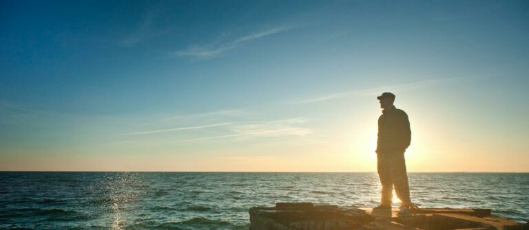 Silhouette Photo of Man Standing Near the Edge of Concrete Pavement